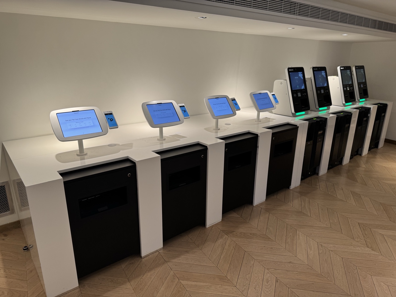A row of Tax Free self-service kiosks on a white counter
